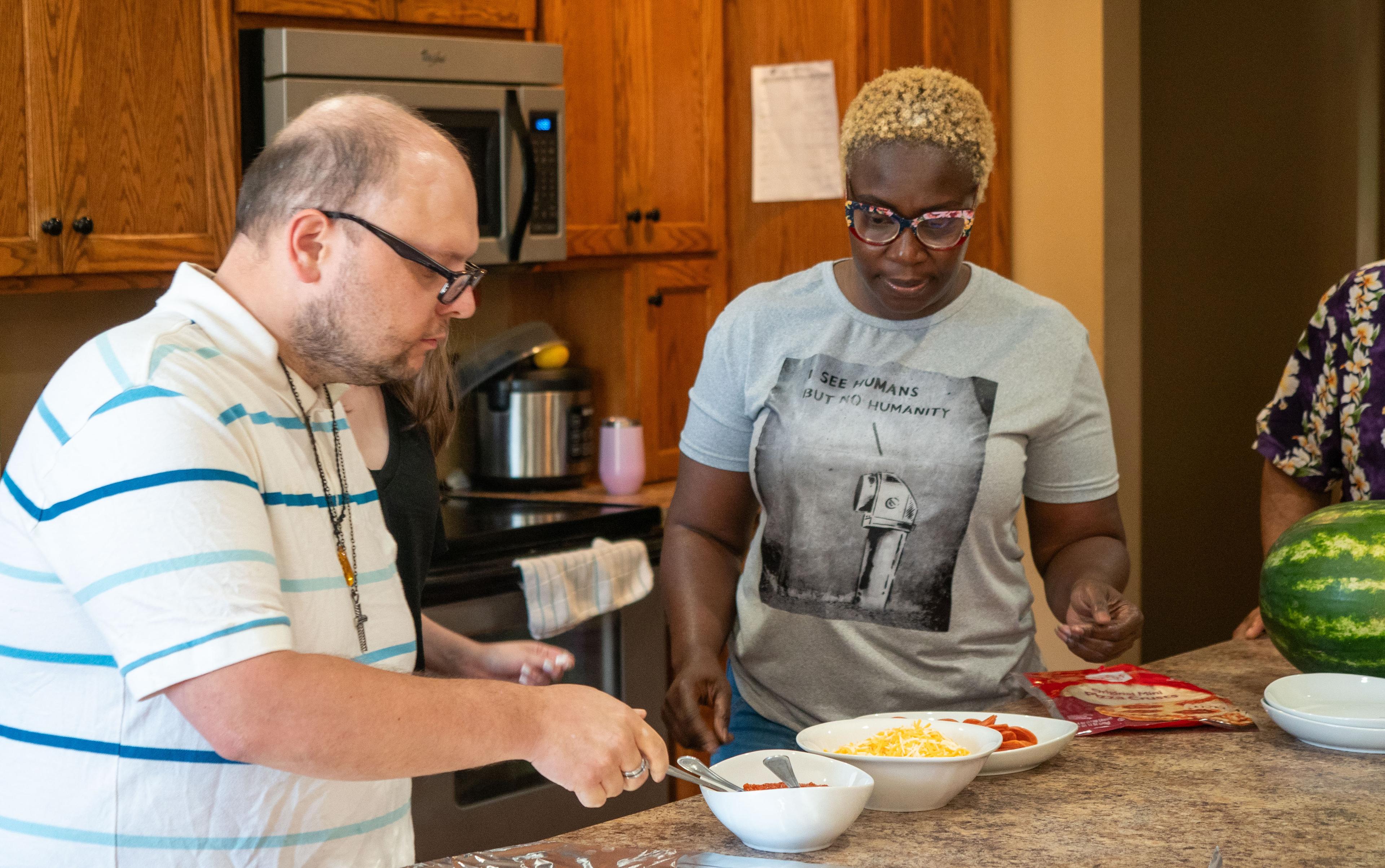 Two people are preparing food in a kitchen. The atmosphere is calm and focused.